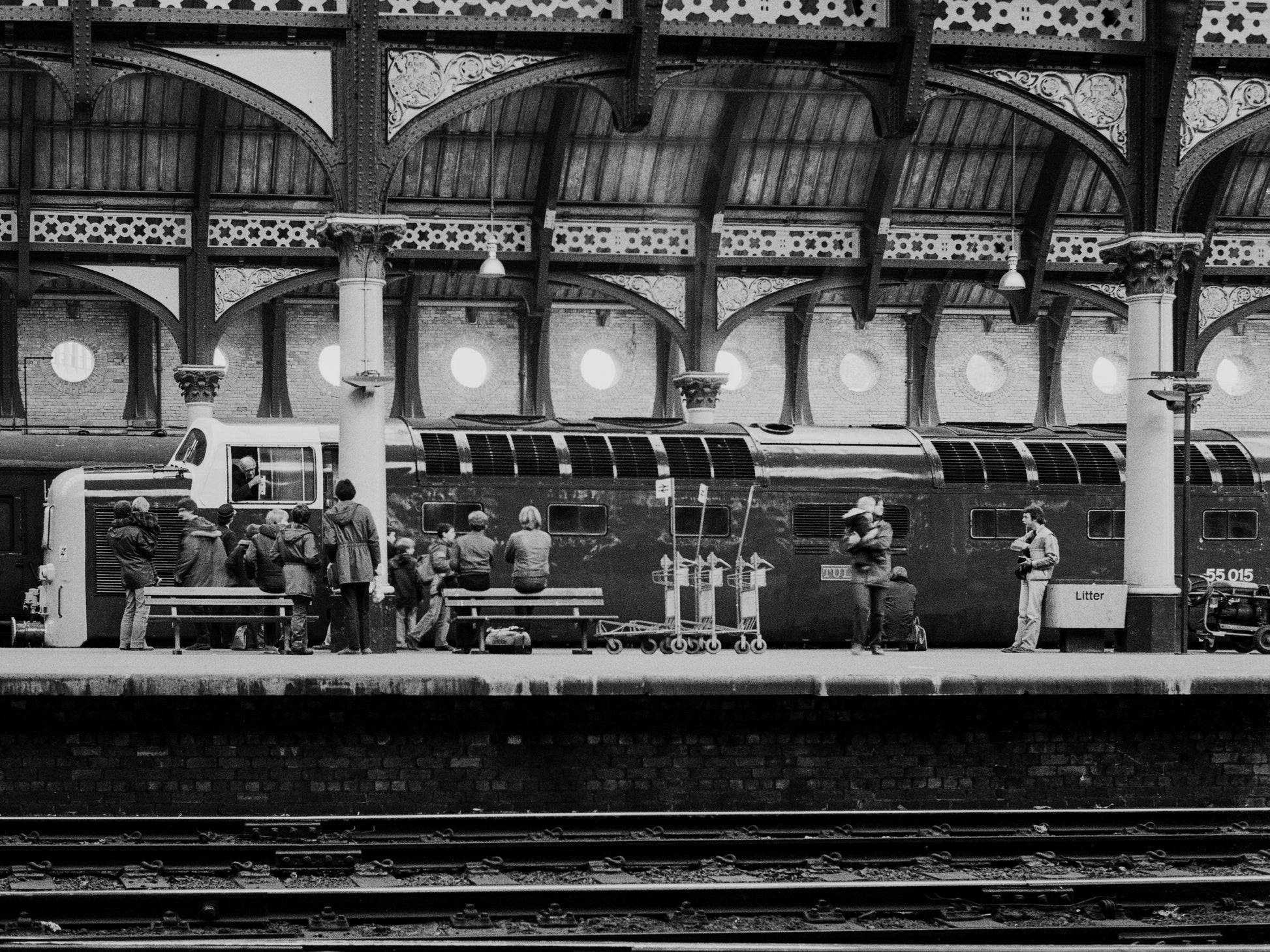 Black-and-white photograph of Class 55 Deltic 55015 Tulyar at York beneath the station canopy, with railway enthusiasts gathered on the platform