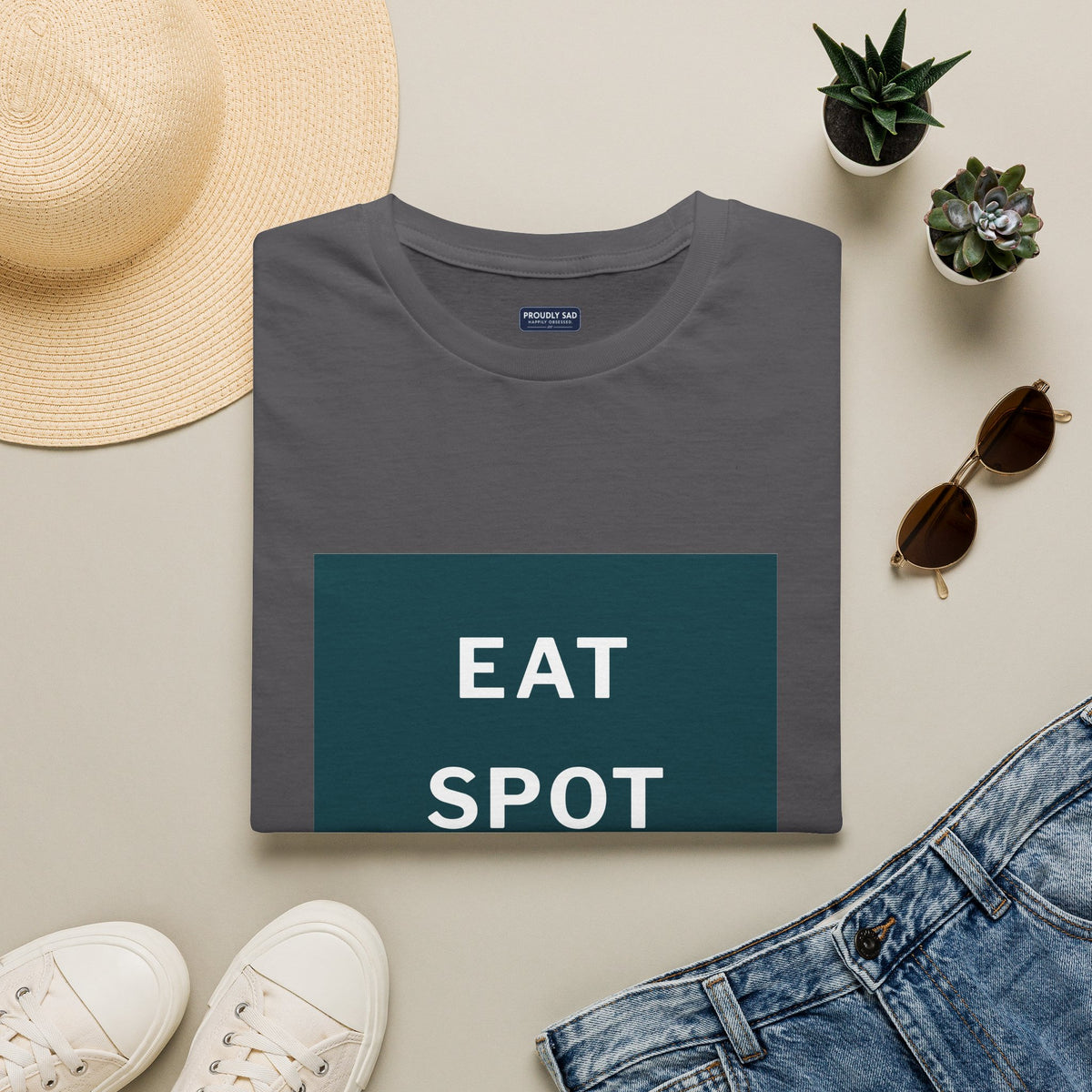 The charcoal Eat, Spot, Sleep, Repeat T-shirt folded flat, the phrase in white on a dark green panel